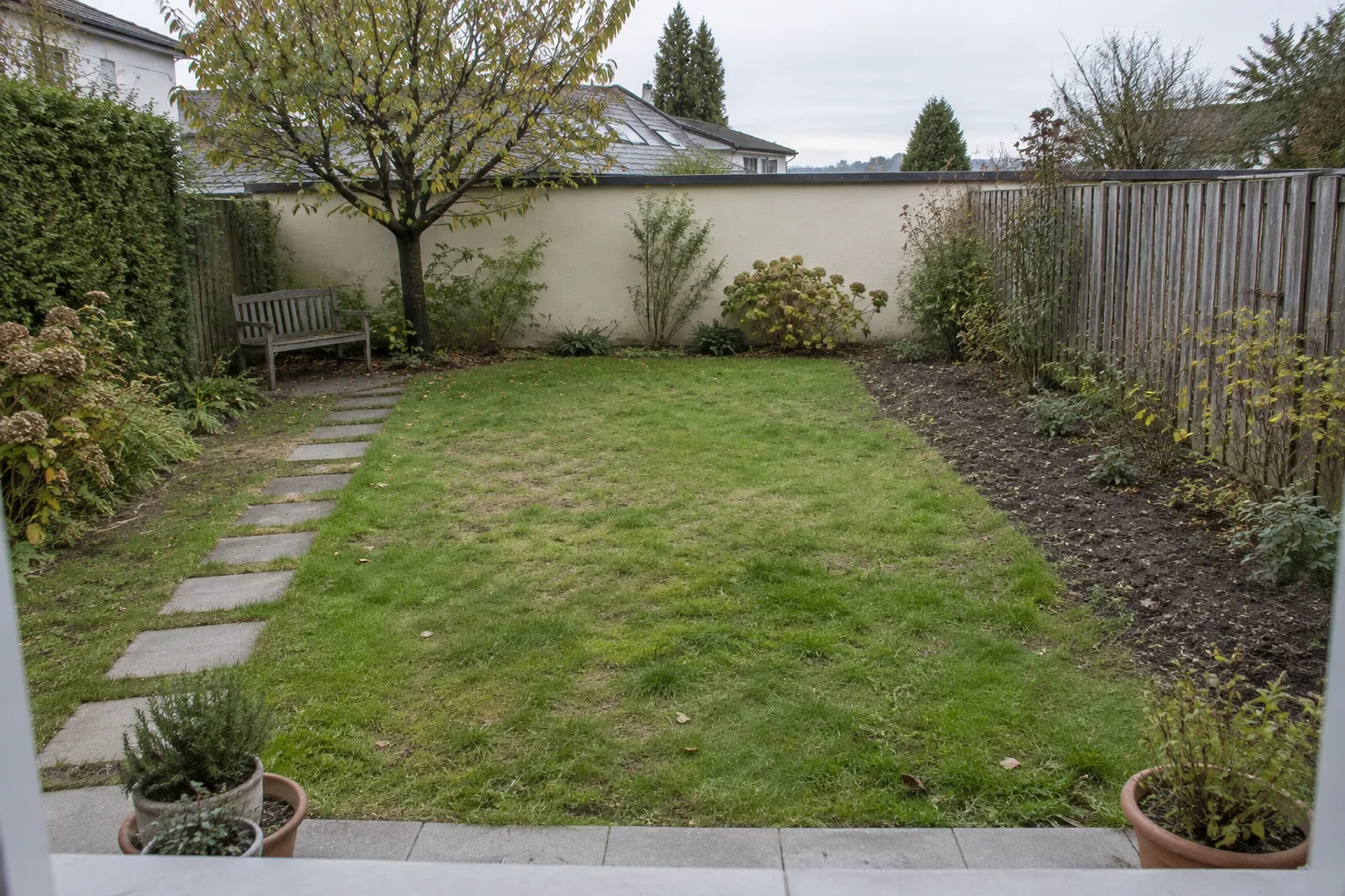Einfacher Garten mit geradem Trittplattenweg und wenig gegliederten Beeten